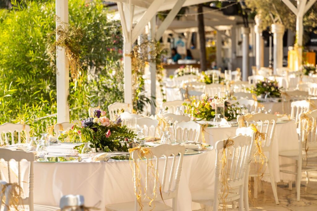 Beautifully arranged outdoor wedding reception with floral centerpieces and white decor.